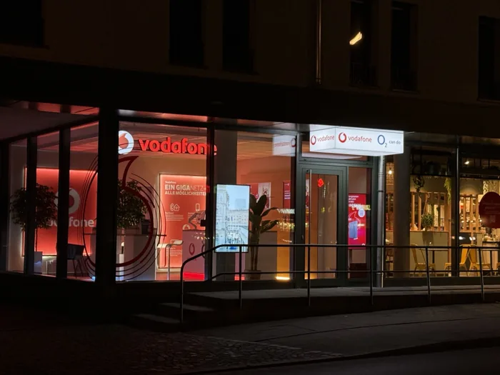 Beleuchtete Schaufenster und Eingang des Vodafone Partnershops Dachau